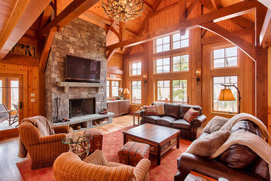 Huge mountain style open concept light wood floor and brown floor living room photo in Boston with brown walls, a standard fireplace, a stone fireplace and a wall-mounted tv