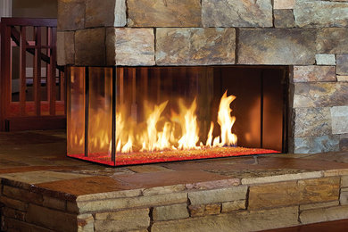 他の地域にあるお手頃価格の中くらいなラスティックスタイルのおしゃれなLDK (無垢フローリング、両方向型暖炉、石材の暖炉まわり、テレビなし、茶色い壁) の写真
