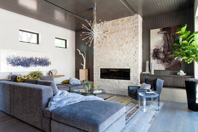 Repräsentatives, Fernseherloses, Mittelgroßes Mid-Century Wohnzimmer im Loft-Stil mit Gaskamin, Kaminumrandung aus Stein, grauer Wandfarbe, grauem Boden und braunem Holzboden in Denver