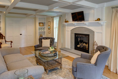 Modelo de salón para visitas cerrado tradicional con paredes beige, suelo de madera clara, todas las chimeneas, marco de chimenea de yeso y televisor colgado en la pared