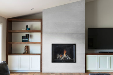 トロントにある中くらいなコンテンポラリースタイルのおしゃれなLDK (グレーの壁、無垢フローリング、標準型暖炉、コンクリートの暖炉まわり、据え置き型テレビ、茶色い床) の写真