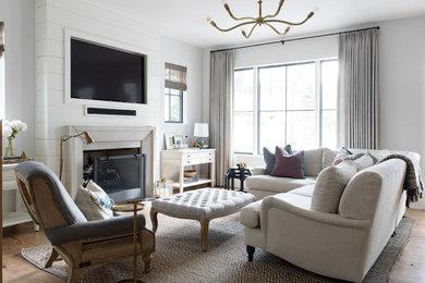 Ejemplo de salón marinero con paredes blancas, suelo de madera clara, todas las chimeneas, televisor colgado en la pared y suelo beige