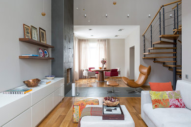 Источник вдохновения для домашнего уюта: большая гостиная комната в скандинавском стиле с серыми стенами, паркетным полом среднего тона, стандартным камином и фасадом камина из плитки