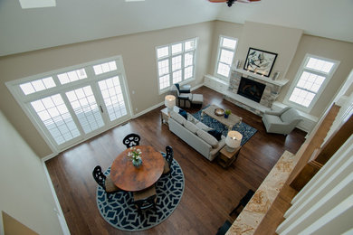 Mid-sized transitional open concept medium tone wood floor living room photo in Milwaukee with beige walls, a standard fireplace and a stone fireplace