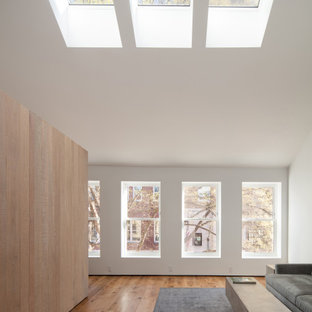 Mittelgroßes, Fernseherloses, Offenes Industrial Wohnzimmer ohne Kamin mit weißer Wandfarbe, hellem Holzboden und gelbem Boden in Sonstige