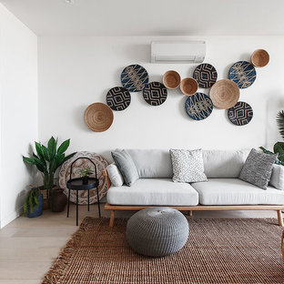 This is an example of a beach style open concept living room in Melbourne with white walls, light hardwood floors and beige floor.
