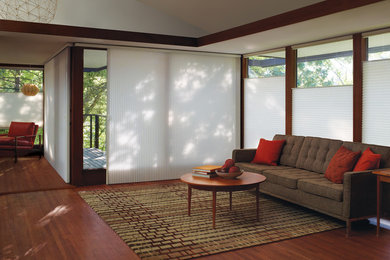 Modelo de salón abierto actual de tamaño medio sin chimenea con paredes beige y suelo de madera en tonos medios