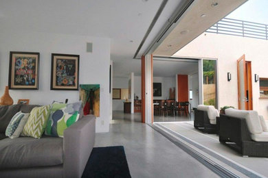 Foto de salón para visitas abierto moderno con paredes blancas, suelo de cemento y pared multimedia