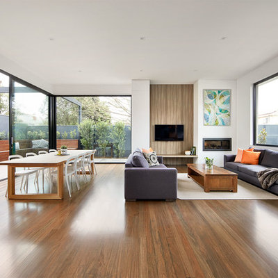 Example of a trendy formal and open concept medium tone wood floor living room design in Melbourne with white walls, a ribbon fireplace and a wall-mounted tv