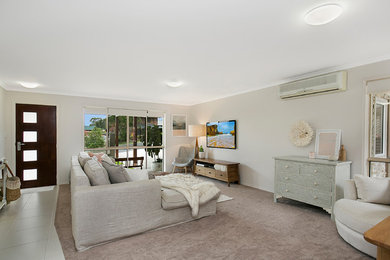 Imagen de salón abierto actual pequeño sin chimenea con paredes beige, moqueta, televisor colgado en la pared y suelo beige