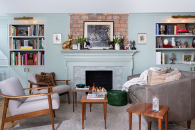 This is an example of a medium sized eclectic open plan living room in New York with green walls, light hardwood flooring, a standard fireplace, no tv, a reading nook and a tiled fireplace surround.