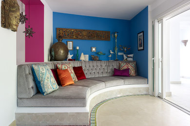 Cette image montre un salon méditerranéen avec un mur bleu et un sol beige.