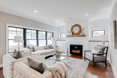 Example of a mid-sized farmhouse formal and open concept dark wood floor and brown floor living room design in Minneapolis with white walls, a standard fireplace, a wood fireplace surround and a concealed tv