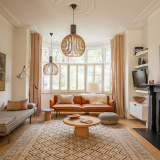 This is an example of a scandinavian living room in London with beige walls, light hardwood flooring, a standard fireplace and beige floors.