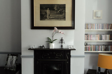 ロンドンにあるお手頃価格の中くらいなヴィクトリアン調のおしゃれなLDK (グレーの壁、無垢フローリング、標準型暖炉、金属の暖炉まわり) の写真
