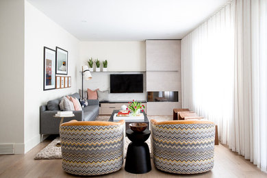 Mittelgroßes, Offenes Modernes Wohnzimmer mit weißer Wandfarbe, hellem Holzboden, Tunnelkamin, Kaminumrandung aus Stein, TV-Wand und beigem Boden in Calgary