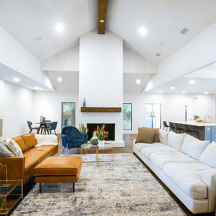 Ispirazione per un grande soggiorno minimalista aperto con angolo bar, pareti bianche, parquet scuro, camino classico, cornice del camino in mattoni, parete attrezzata, pavimento marrone, soffitto a volta e pareti in mattoni