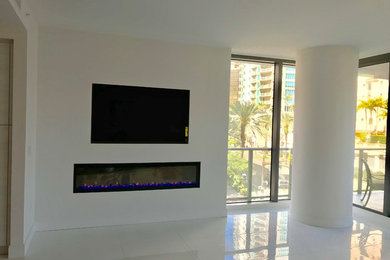 Example of a mid-sized minimalist porcelain tile and white floor living room design in Tampa with white walls, a ribbon fireplace, a plaster fireplace and a media wall