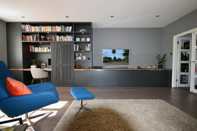 Imagen de salón minimalista grande sin chimenea con paredes grises, suelo de madera clara y televisor colgado en la pared