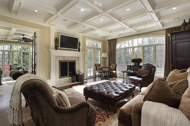 Example of a mid-sized classic open concept dark wood floor and brown floor living room design in Los Angeles with beige walls, a standard fireplace, a stone fireplace and a wall-mounted tv