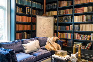 Modelo de biblioteca en casa ecléctica con paredes azules y suelo de madera en tonos medios