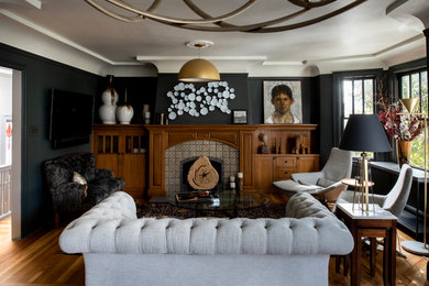 Diseño de salón clásico renovado con paredes negras, suelo de madera en tonos medios, todas las chimeneas, marco de chimenea de baldosas y/o azulejos y suelo marrón