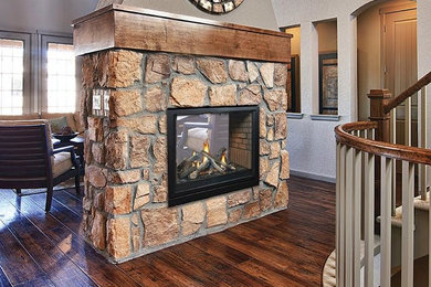Example of a mid-sized classic enclosed dark wood floor and brown floor living room design in Kansas City with beige walls, a two-sided fireplace, a stone fireplace and no tv