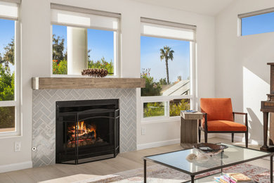 サンディエゴにある高級な広いビーチスタイルのおしゃれなリビング (白い壁、セラミックタイルの床、標準型暖炉、タイルの暖炉まわり、据え置き型テレビ、グレーの床) の写真