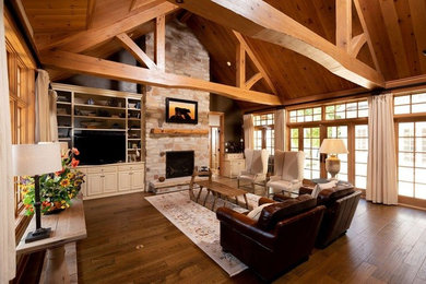 Large mountain style open concept medium tone wood floor and brown floor living room photo in Other with a standard fireplace and a stone fireplace