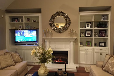 ハンティントンにある中くらいなトランジショナルスタイルのおしゃれなリビング (茶色い壁、無垢フローリング、標準型暖炉、木材の暖炉まわり、据え置き型テレビ、茶色い床) の写真