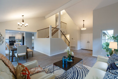 Diseño de salón abierto actual de tamaño medio con paredes grises y suelo de madera clara