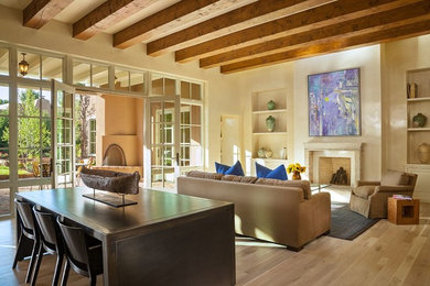 Example of a large southwest light wood floor living room design in Albuquerque with beige walls, a standard fireplace and a stone fireplace