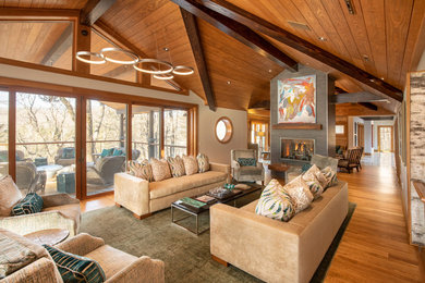 Large transitional open concept medium tone wood floor living room photo in Charlotte with beige walls, a two-sided fireplace and a stone fireplace