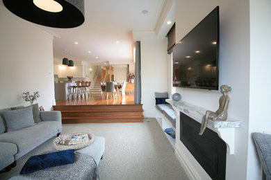 メルボルンにあるトラディショナルスタイルのおしゃれな独立型リビング (白い壁、カーペット敷き、壁掛け型テレビ、グレーの床) の写真