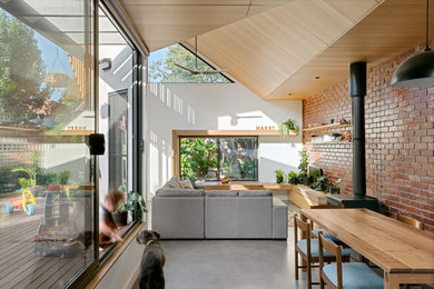 Mittelgroßes, Offenes Modernes Wohnzimmer mit weißer Wandfarbe, Betonboden, Kaminofen, freistehendem TV und grauem Boden in Melbourne