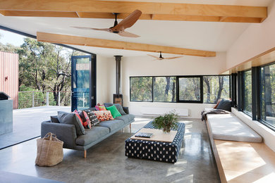 Example of a danish concrete floor and gray floor living room design in Geelong with white walls, a wood stove and a metal fireplace