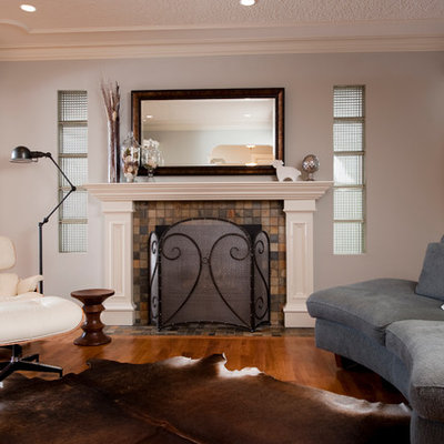 Example of a huge trendy open concept medium tone wood floor living room library design in Calgary with a standard fireplace, a tile fireplace, no tv and gray walls