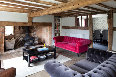 Photo of a rural formal living room in Sussex with white walls, a wood burning stove and light hardwood flooring.