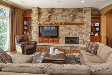 Example of a mid-sized classic open concept light wood floor living room design in Chicago with brown walls, a standard fireplace, a stone fireplace and a media wall