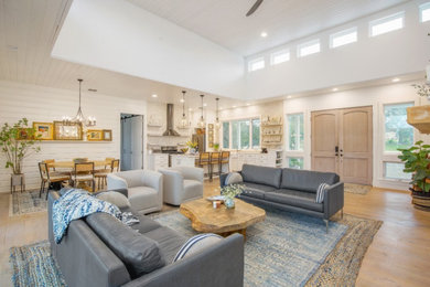 Example of a mid-sized cottage open concept light wood floor, white floor, coffered ceiling and shiplap wall living room design in Austin with white walls, a two-sided fireplace and a stone fireplace