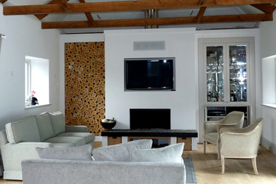 Bild på ett funkis vardagsrum, med vita väggar, ljust trägolv, en standard öppen spis och en spiselkrans i gips