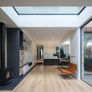 Mittelgroßes, Offenes Modernes Wohnzimmer mit hellem Holzboden, Kaminofen, Kaminumrandung aus Backstein und verstecktem TV in London