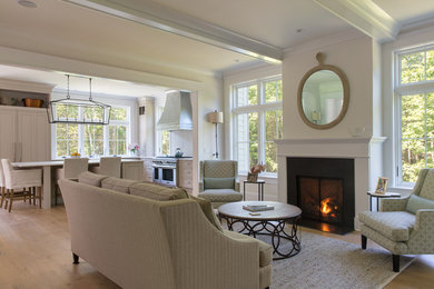 Example of a small farmhouse formal medium tone wood floor living room design in Portland Maine with a standard fireplace, a wood fireplace surround, no tv and beige walls