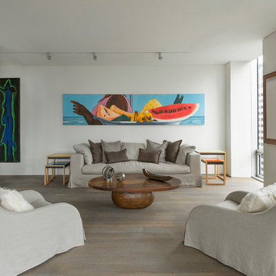 Example of a large trendy formal and open concept medium tone wood floor and beige floor living room design in New York with white walls, no fireplace and a concealed tv