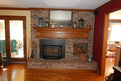 他の地域にある高級な中くらいなトラディショナルスタイルのおしゃれなリビング (ベージュの壁、無垢フローリング、標準型暖炉、レンガの暖炉まわり、茶色い床) の写真