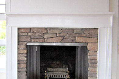 Exemple d'un salon chic de taille moyenne avec un mur blanc, une cheminée standard et un manteau de cheminée en pierre.
