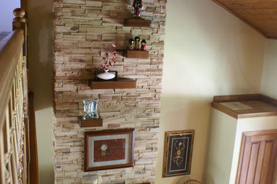 Modelo de salón tipo loft rural de tamaño medio sin televisor con paredes beige, suelo de madera en tonos medios, todas las chimeneas y marco de chimenea de piedra
