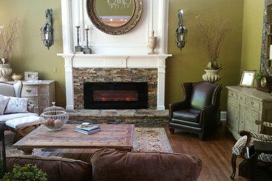 Klassisches Wohnzimmer mit grüner Wandfarbe, hellem Holzboden, Gaskamin und Kaminumrandung aus Stein in Atlanta