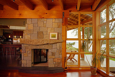 Diseño de salón abierto de estilo americano de tamaño medio con paredes beige, suelo de madera en tonos medios, chimenea de doble cara y marco de chimenea de piedra