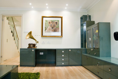 Medium sized modern enclosed living room in London with light hardwood flooring and a concealed tv.